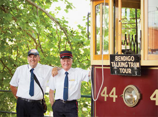 Two Tram Drivers standing next to a burgundy Vintage Talking Tram